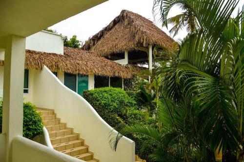 翡翠海岸本吉瑟斯酒店的一座建筑,有楼梯通往一座带稻草屋顶的建筑