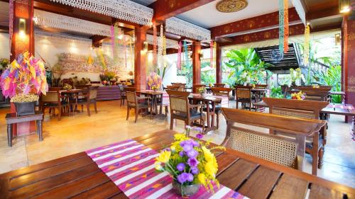 清迈Yaang Come Village Hotel - SHA Extra Plus的一间带木桌和椅子的餐厅,