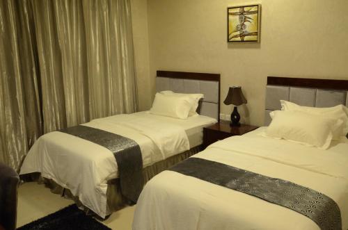 阿吉曼Reef Hotel Aparts (Tabasum Group)的酒店客房,配有两张带白色床单的床