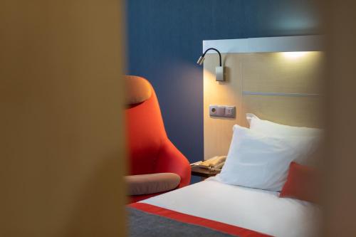 莱萨·达·帕尔梅拉波尔图艾克波诺智选假日酒店的酒店客房,配有一张床和一张红色椅子
