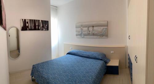 利多迪耶索罗RESIDENCE EL PALMAR FRONTE MARE, FRONTE SPIAGGIA (5 metri), FRONTE PISCINA (4 metri)的一间卧室配有蓝色的床和镜子