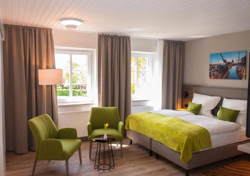 Sulsdorf auf FehmarnLindenhof Hotel Garni的一间卧室配有一张床和两张绿色椅子