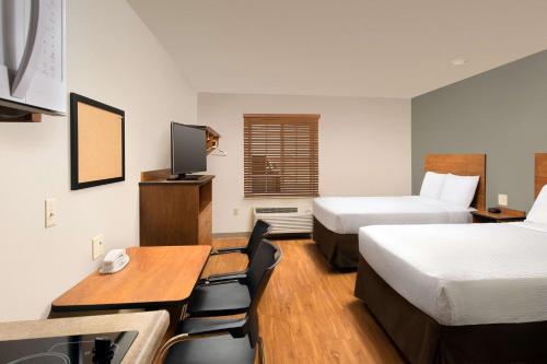 Air Base City霍布斯伍德思普汽车旅馆的酒店客房带两张床和一张桌子以及椅子。