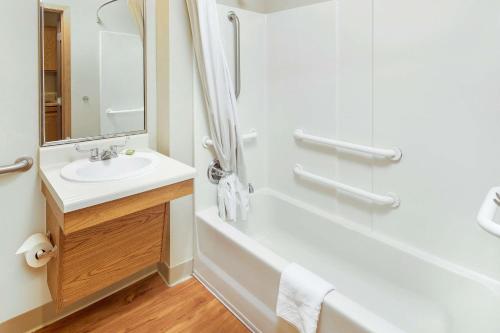 埃佩克斯WoodSpring Suites Raleigh Apex的白色的浴室设有水槽和淋浴。