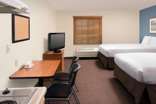 圣安东尼奥WoodSpring Suites San Antonio North Live Oak I-35的酒店客房设有两张床、一张桌子和一台电视。