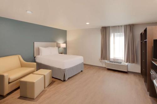 休斯顿WoodSpring Suites Houston Northwest的配有一张床和一把椅子的酒店客房