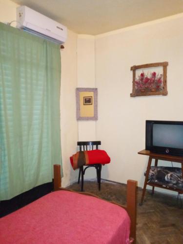 罗萨里奥Hostel en rosario的一间卧室配有一张床、一台电视和一张桌子