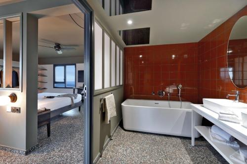 圣丹尼斯DINA MORGABINE SAINT DENIS的带浴缸、水槽和床的浴室