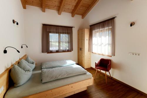 维皮泰诺Nestlhof的一间卧室配有一张床和一张红色椅子