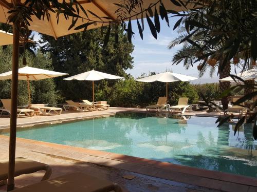 拉拉塔可库斯特珍内蒂希特住宿加早餐旅馆的一个带遮阳伞和桌椅的游泳池