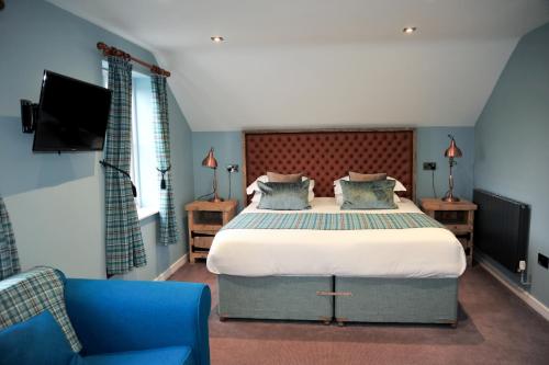 Tal-y-CafnThe Tal-Y-Cafn Hotel的一间卧室配有一张大床和一张蓝色椅子