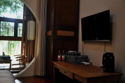 杭州杭州一舍湛然民宿(原杭州灵隐湛然堂度假小酒店)的一间卧室配有电视和一张带瓶子的桌子。