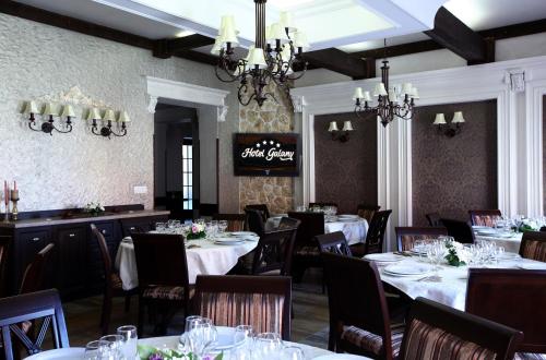 勒德乌齐加拉尼酒店的用餐室配有白色桌椅和吊灯。