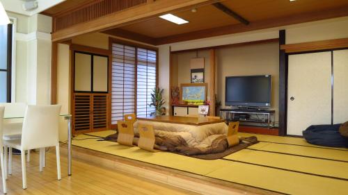 富士河口湖K's House MtFuji -ケイズハウスMt富士- Travelers Hostel- Lake Kawaguchiko的客厅配有大床和电视