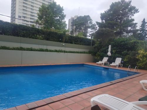 埃斯特角城Apartamento Marina de roosvelt con piscina climatizada的一座带两把椅子的游泳池以及一座建筑