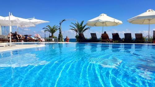 内塞伯尔阿芙罗狄蒂海滩酒店的一个带椅子和遮阳伞的大型游泳池