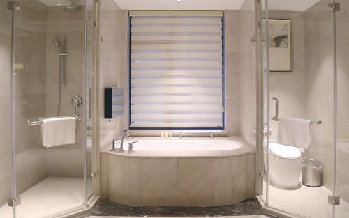 西安西安豪享来温德姆至尊公寓的一间带浴缸和淋浴的浴室,并设有一个窗户