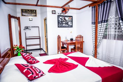 蒂瑟默哈拉默Yala New Nehansa Resort的一间卧室配有一张带红色枕头的床和一张桌子