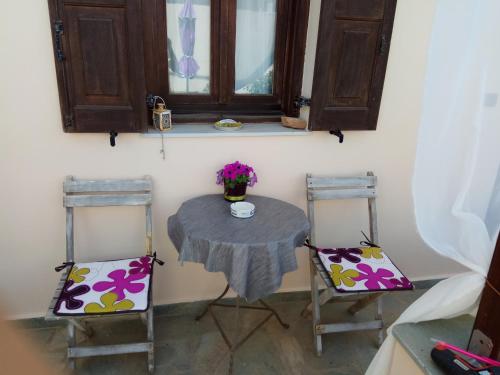 埃尔莫波利斯maria's rooms syros的一张桌子、两把椅子和一张带鲜花的桌子