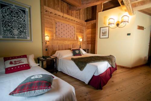 布吕松Laghetto Alpine Hotel & Restaurant的一间带两张床铺的卧室,位于带木墙的房间内