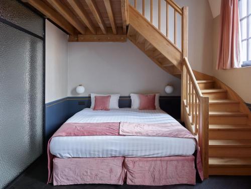 列日Amosa Liège City Centre Hotel的一间卧室配有一张带粉色床单的床和楼梯。