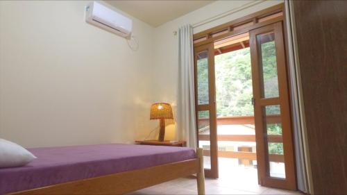 皮涅拉Residencial do Cadinho的一间卧室设有一张床,并有通往阳台的门
