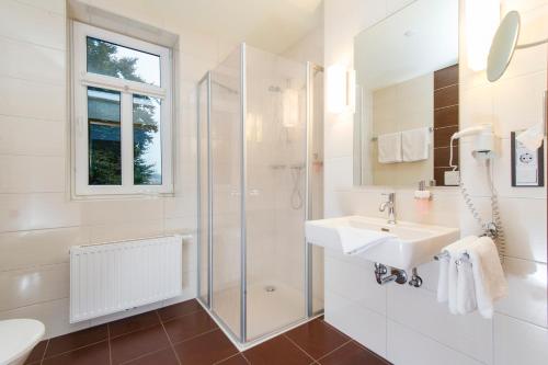 哈伦格瑞酒店的白色的浴室设有水槽和淋浴。