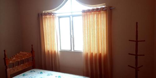 波苏斯-迪卡尔达斯Hostel e Pousada Solar的一间卧室配有床和带窗帘的窗户