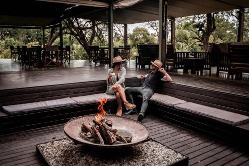 曼耶雷蒂野生动物园Honeyguide Tented Safari Camp - Khoka Moya的两个人坐在火坑旁的长凳上
