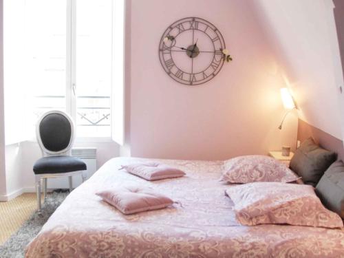 沙特尔马诺伊城市休闲酒店的卧室配有一张床,墙上挂着一个钟