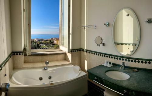 埃尔科拉诺密丽欧多罗公园酒店的带浴缸、水槽和镜子的浴室
