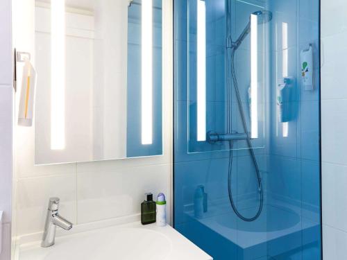 图卢兹赫尔莫斯酒店的带淋浴的浴室和蓝色玻璃门
