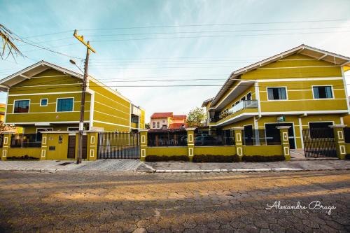 南圣弗朗西斯科ApartPousada Residencial dos Reis的两栋黄色房屋,在街上有围栏