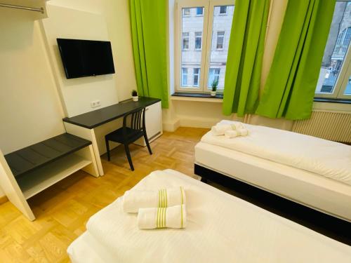 亚琛bestprice Hotel Aachen Hauptbahnhof的客房设有两张床和一张书桌及一台电视。