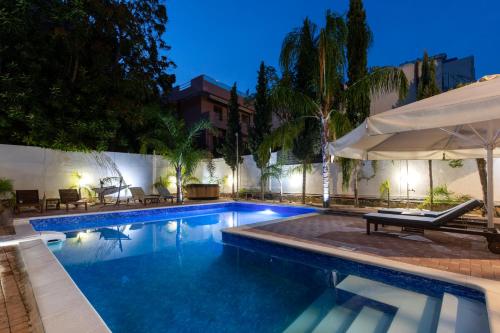 罗德镇Villa 56 Luxury apartments的一座带遮阳伞的游泳池位于大楼旁