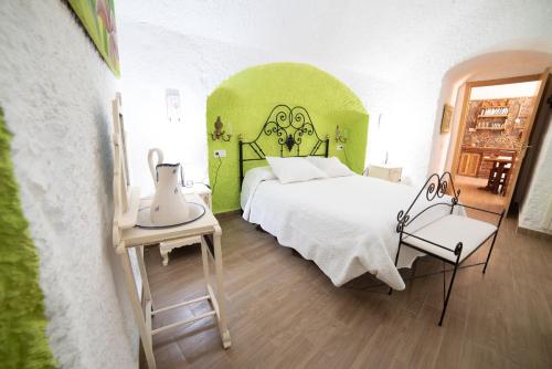 瓜迪克斯Cuevas Cortijo Gachas的卧室配有白色的床和绿色的墙壁