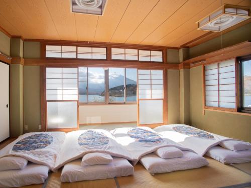 山中湖村Tabist Lakeside in Fujinami Yamanakako的配有窗户的客房内的一张大床和四个枕头