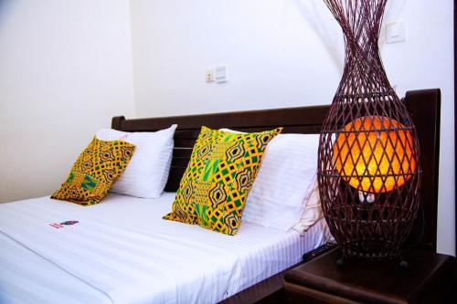 阿比让塞帕酒店的一间卧室配有一张带色彩缤纷枕头的床和一盏灯。