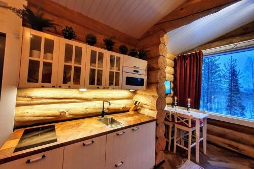 罗瓦涅米Cozy Log Cabin by Invisible Forest Lodge的厨房配有带水槽的柜台和窗户。