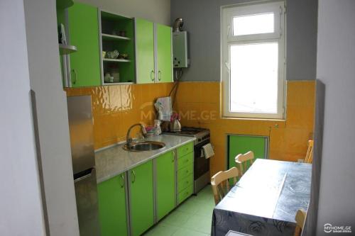 博尔若米Our house的厨房配有绿色橱柜、桌子和窗户。