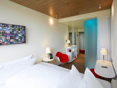 鲁瓦西昂法兰西巴黎戴高乐机场世民酒店 的卧室配有白色的床和红色椅子