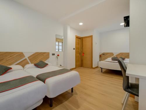 安普埃罗Hostal Restaurante La pinta的酒店客房配有两张床和一张书桌