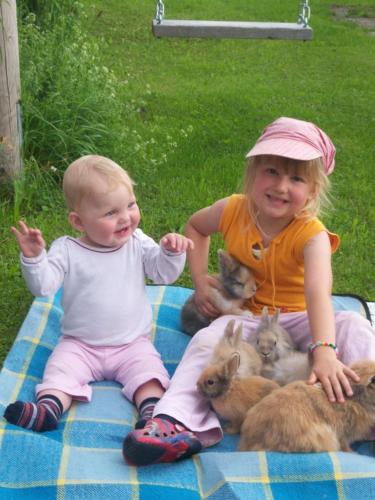 希明格Irgenbauer的一个小女孩和一个婴儿坐在毯子里,带着兔子