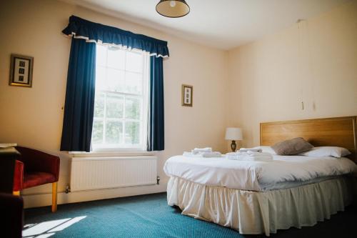 比格尔斯威德The Stratton House Hotel的一间卧室设有一张大床和一个窗户。
