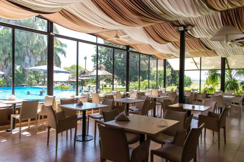 维多利亚Campo & Golf的一间带桌椅的餐厅和一个游泳池