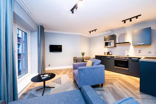都柏林Staycity Aparthotels, Dublin, Christchurch的一间带蓝色沙发的客厅和一间厨房