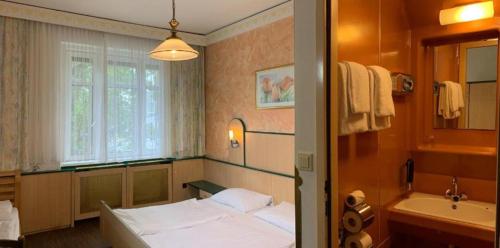 维也纳哈里甘酒店的一间卧室配有一张床、一个浴缸和一个水槽
