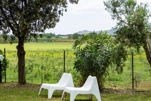 卡斯蒂里昂纳·德拉佩Le Pettegole del Boschetto的两把白色椅子坐在栅栏前