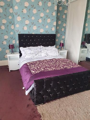 米德尔斯伯勒Southfield lodge的一间卧室配有一张带紫色床单和花卉壁纸的床