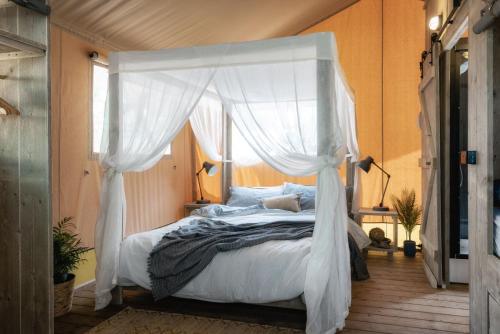 卡斯尔梅恩Castlemaine Gardens Luxury Safari Tents的卧室配有带白色窗帘的天蓬床